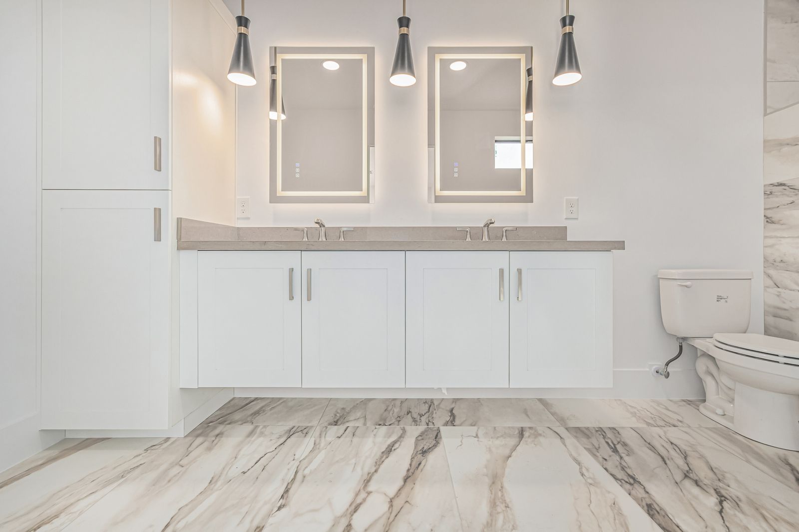 Double vanity with lit mirrors over a marble-look tile floor