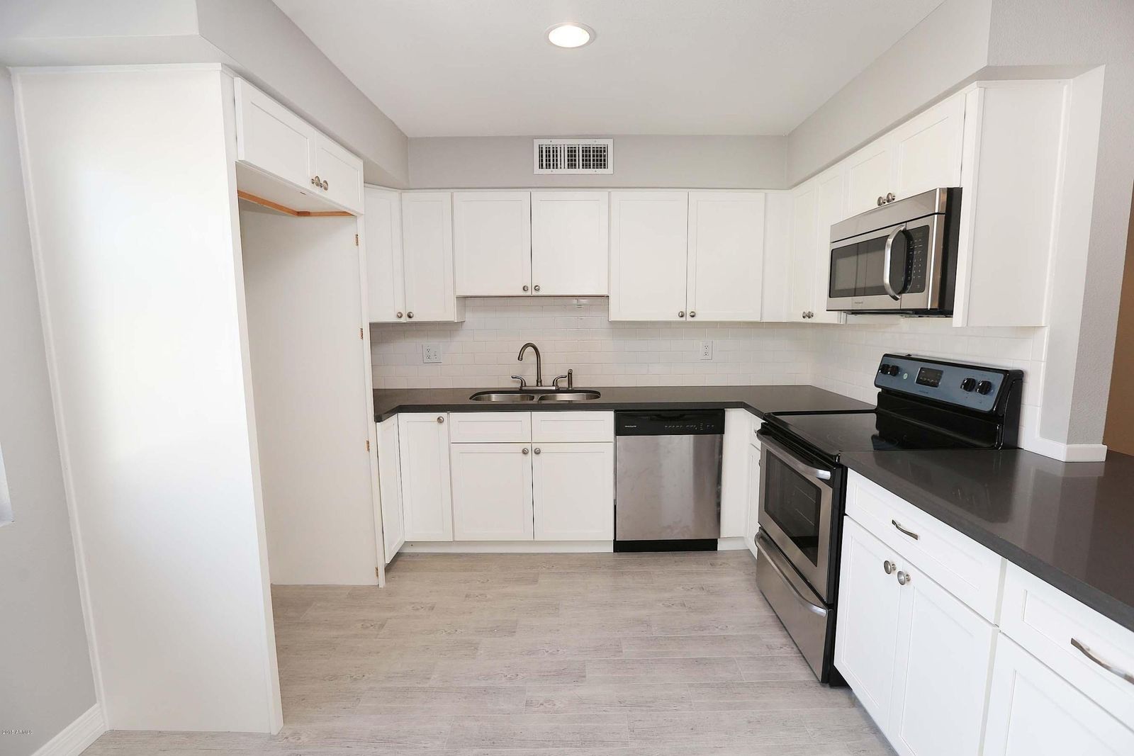 White kitchen with dark countertops and new tile floor