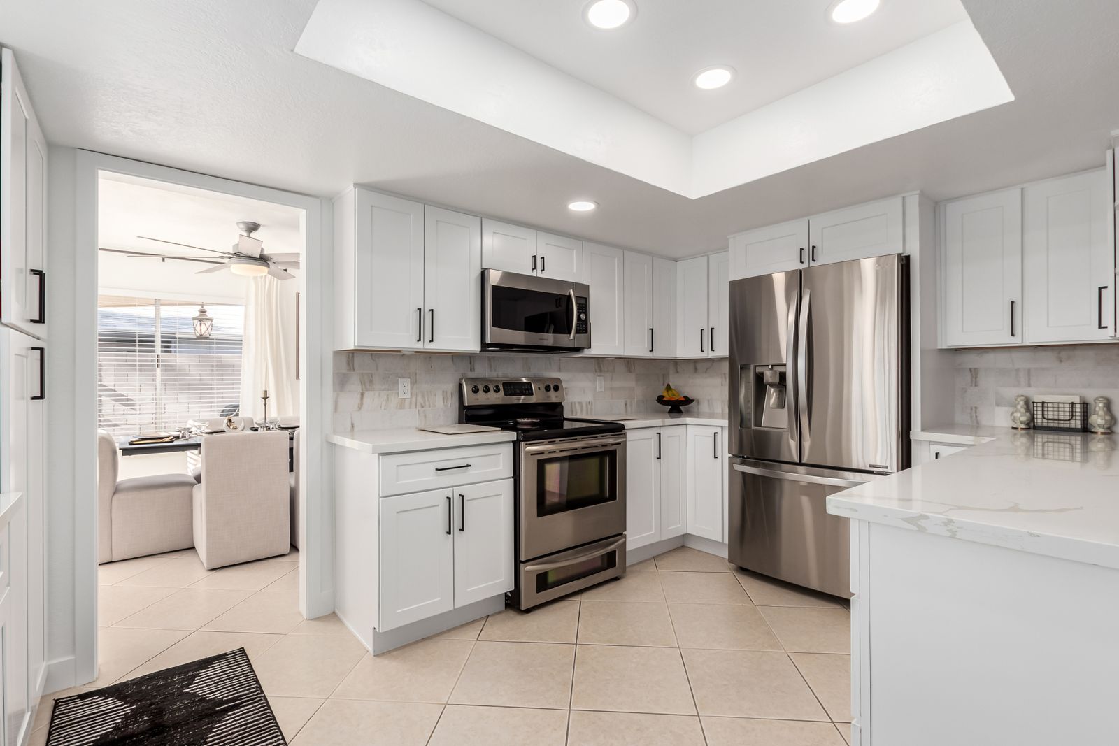 White shaker kitchen with quartz counters and tile floor