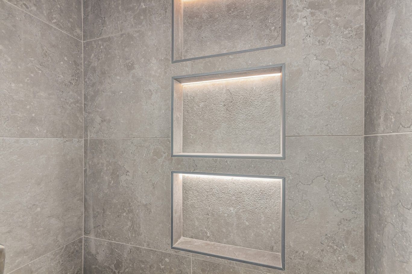 Shower wall with three lit recessed niches